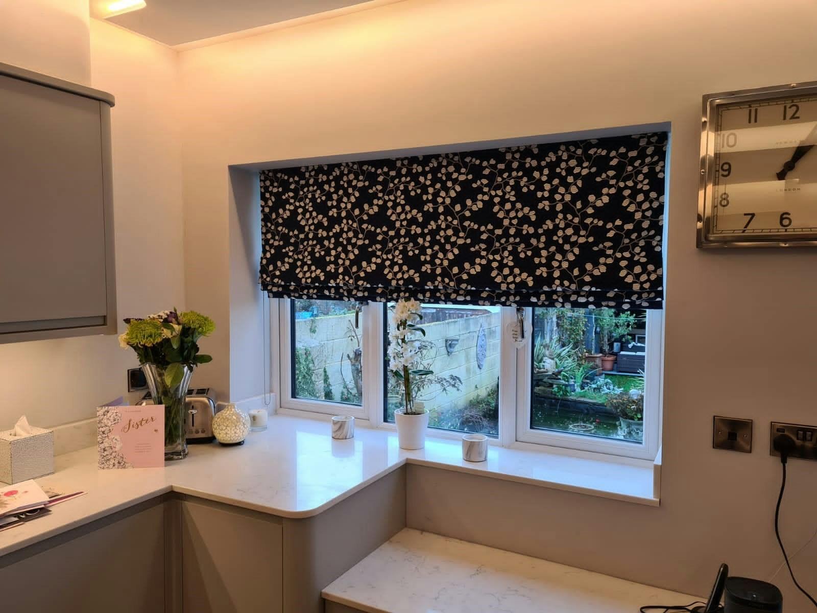 Some black and white floral patterned roman blinds overlooking a courtyard garden
